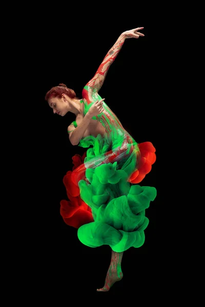 Портрет молодої ніжної жінки, вкрито червоно-зеленою фарбою та барвниками, танцює ізольовано на чорному тлі — стокове фото