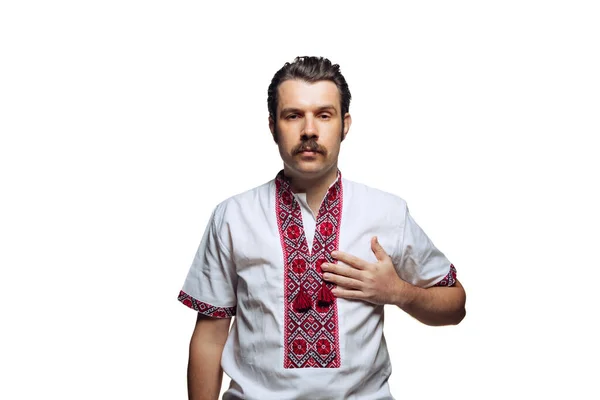 Muotokuva vakava mies ukrainalaisessa kansallisessa kankaassa kirjonta paita lomaillut käsi sydämellä eristetty yli valkoinen studio tausta — kuvapankkivalokuva