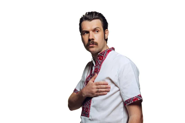 Porträtt av allvarlig man i ukrainska nationella tyg - broderi skjorta holiding hand på hjärtat isolerad över vit studio bakgrund. Sidovy — Stockfoto