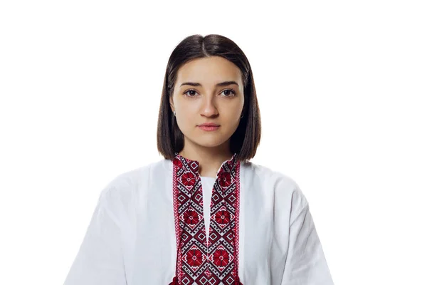 Портрет молодой красивой женщины в традиционной украинской ткани - вышивальная рубашка, внимательно смотрящая на камеру, изолированную на белом фоне студии — стоковое фото