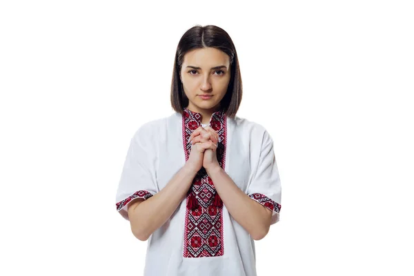 Портрет эмоциональной женщины в традиционной украинской ткани - вышивальная рубашка, вышиванка изолирована на белом студийном фоне. Молясь за Украину — стоковое фото