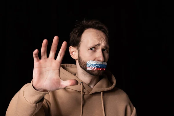 Gros plan portrait de jeune homme émotif avec trois couleurs de ruban adhésif sur sa bouche isolé sur fond sombre. Censure, concept de liberté d'expression. — Photo