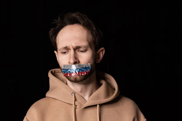 Gros plan portrait de jeune homme émotif avec trois couleurs de ruban adhésif sur sa bouche isolé sur fond sombre. Censure, concept de liberté d'expression. — Photo