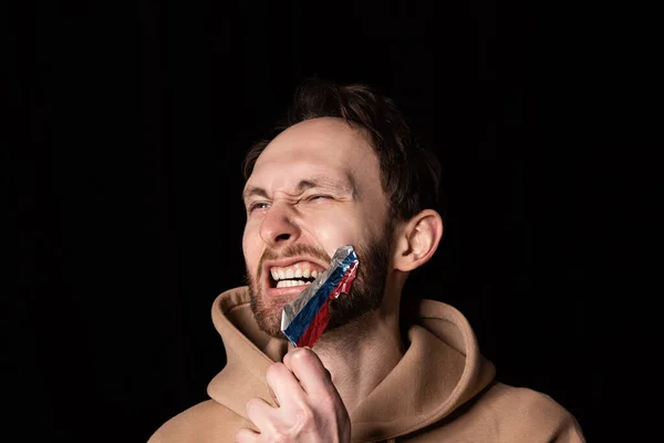 Nahaufnahme Porträt eines jungen emotionalen Mannes reißt drei Farben Klebeband aus seinem Mund isoliert auf dunklem Hintergrund. Zensur, Konzept der Meinungsfreiheit. — Stockfoto