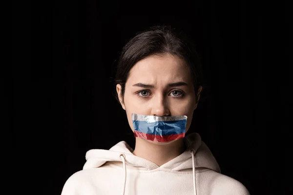 Halflegth portret van jong emotioneel overstuur meisje met drie kleuren duct tape over haar mond geïsoleerd op donkere achtergrond. Censuur, vrijheid van meningsuiting. — Stockfoto