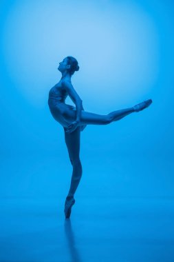 Merhamet. Genç ve zarif balerin mavi stüdyo arka planında neon ışıklarıyla izole edilmiş. Sanat, esneklik, ilham kavramı.