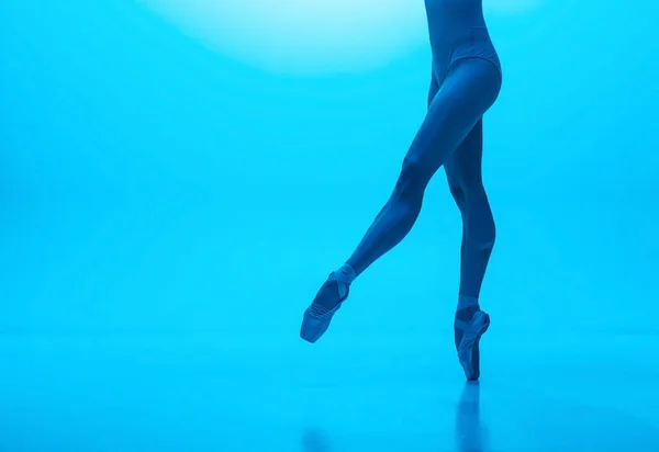 Pernas de bailarinas close-up em sapatos pontiagudos isolados em fundo estúdio cor marinha em néon. Arte, movimento, ação, flexibilidade, conceito de inspiração. — Fotografia de Stock