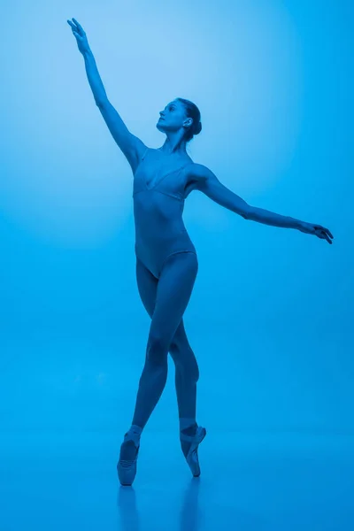 Grace... Jovem e graciosa dançarina de balé isolado em fundo estúdio azul em luz de néon. Arte, flexibilidade, conceito de inspiração. — Fotografia de Stock