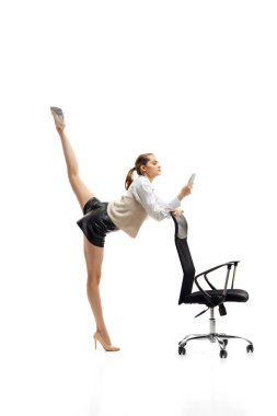 İş kıyafetleri içinde, beyaz stüdyo arka planında sicim oluşturan esnek bir kadının portresi.