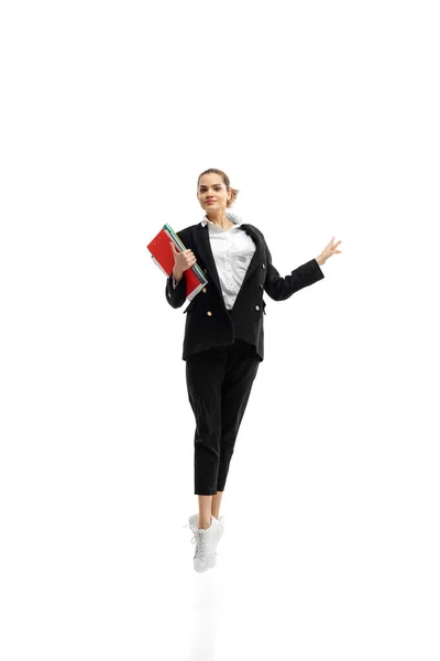 Динамічний портрет молодої бізнес-леді в чорному костюмі, стрибки з папками ізольовані на білому фоні студії — стокове фото