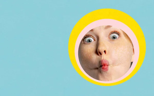Colagem de arte contemporânea. Close-up rosto feminino com expressão engraçada espreita através de círculo multicolorido em fundo azul — Fotografia de Stock