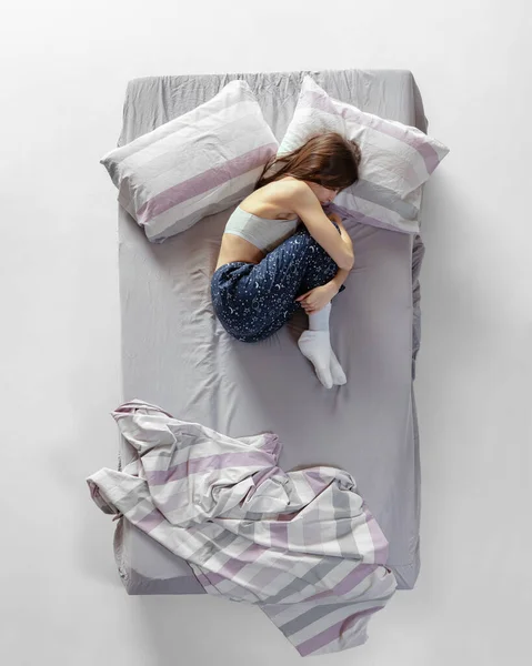 Страшно. Портрет молодой девушки в домашней одежде, пижаме, спящей в большой серой кровати. Здоровья, домашнего интерьера, отдыха, семьи, мечты — стоковое фото