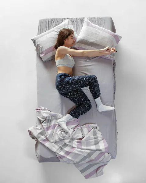 Top view portré fiatal lány visel otthoni viselet, pizsama alszik nagy szürke ágy. Fogalom az egészség, otthon belső, pihenni idő, család, álmok — Stock Fotó