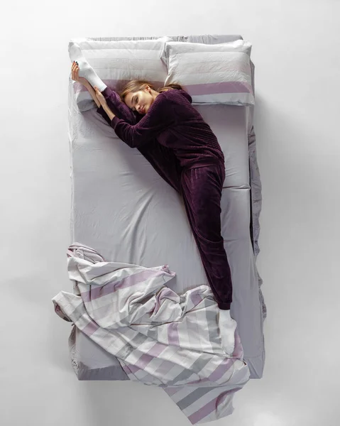 Kreatív portré fiatal lányról, aki borszínű házikosztümöt visel, pizsamában alszik nagy ágyban. Fogalom az egészség, otthon belső, pihenni idő, család, álmok — Stock Fotó