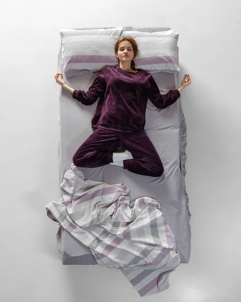 Творческий портрет молодой девушки, одетой в винный цвет домашней одежды, пижамы, спящей в большой кровати. Здоровья, домашнего интерьера, отдыха, семьи, мечты — стоковое фото