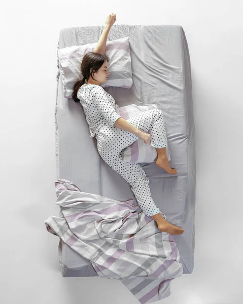 Flygfoto ung sovande flicka i vit pyjamas liggande i stor grå säng. Begreppet hälsa, hem inredning, avkoppling tid, familj, drömmar — Stockfoto