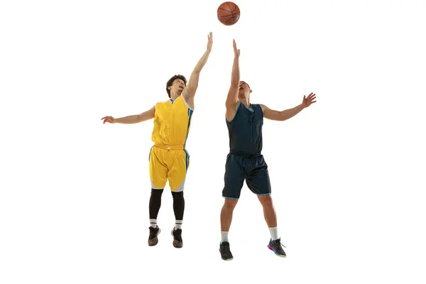Dynamiskt porträtt av två unga basketspelare hoppar med bollen isolerad på vit studio bakgrund. Rörelse, aktivitet, idrottskoncept. — Stockfoto