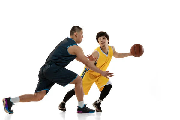 Retrato dinámico de dos jóvenes jugadores de baloncesto jugando al baloncesto aislados sobre fondo blanco del estudio. Movimiento, actividad, conceptos deportivos. — Foto de Stock