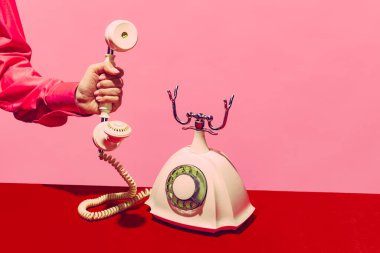 Pop sanat fotoğrafçılığı. Retro nesneler, aletler. Pembe ve kırmızı arka planda izole edilmiş eski model telefonlardan oluşan bir kadın el kamerası. Eski moda, eski moda