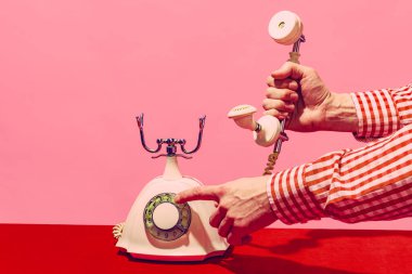 Pop sanat fotoğrafçılığı. Retro nesneler, aletler. Pembe ve kırmızı arka planda izole edilmiş eski model telefonlardan oluşan bir kadın el kamerası. Eski moda, eski moda