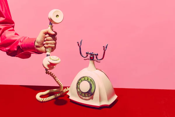 ポップアートの写真。レトロな物や道具。ピンクと赤の背景に隔離されたヴィンテージ電話の女性の手の携帯電話を保持。ヴィンテージ、レトロファッションスタイル — ストック写真