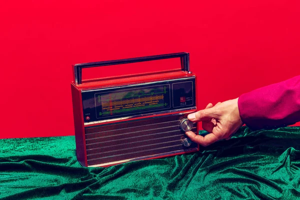 Retro radio. Kvinnlig hand vidrör radiomottagare isolerad på röd och grön bakgrund. Vintage, retromode stil. Pop konst fotografi. — Stockfoto