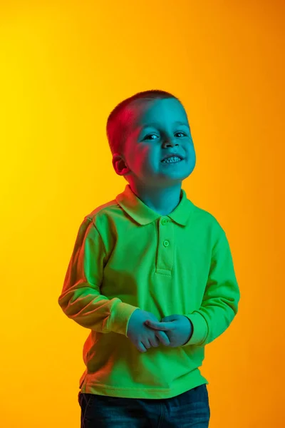 Portrait of cute little boy smiling isolated on yellow studio backgroud in neon light. Concept of child emotions, facial expression, childhood — Stock Photo, Image