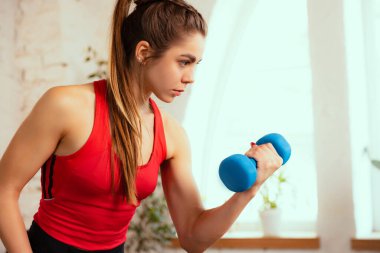 Evde spor malzemeleriyle antrenman yapan güzel bir kızın yakın plan portresi. Spor, spor, aerobik, spor yaşam tarzı kavramı.