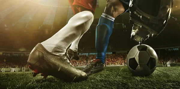 Detailní záběr nohy fotbalu, fotbalisté v akci, pohyb na stadionu s baterkami a přeplněné stánky. Pojetí sportu, soutěže, pohybu, překonávání. — Stock fotografie