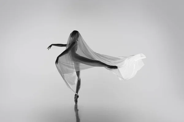 Zwart-wit portret van sierlijke ballerina dansen met stof, doek geïsoleerd op grijze studio-achtergrond. Genade, kunst, schoonheid concept. Gewichtloos, flexibel. — Stockfoto
