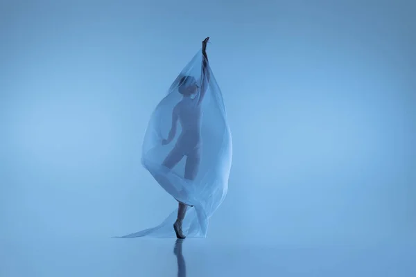 Retrato de mujer flexible, elegante bailarina bailando con tela, tela aislada sobre fondo azul del estudio. Gracia, arte, concepto de belleza. Sin peso, ternura. —  Fotos de Stock