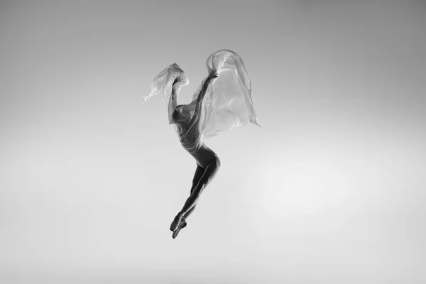 Retrato preto e branco de bailarina graciosa dançando com tecido, pano isolado em fundo estúdio cinza. Graça, arte, conceito de beleza. Sem peso, flexível. — Fotografia de Stock