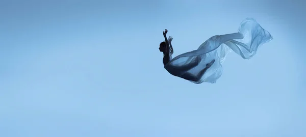Portret van een flexibele vrouw, sierlijke ballerina dansen met stof, doek geïsoleerd op blauwe studio achtergrond. Genade, kunst, schoonheid concept. Gewichtloos, tederheid. — Stockfoto