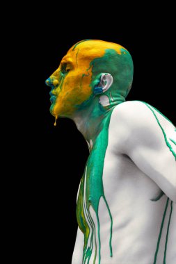 Gözleri kapalı duran genç adamın yaratıcı portresi. Renkli boyalar, boyalar kafasından, omuzlarından ve vücudundan aşağı akıyor..