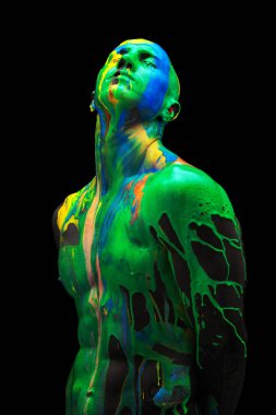 Gözleri kapalı duran genç adamın yaratıcı portresi. Renkli boyalar, boyalar kafasından, omuzlarından ve vücudundan aşağı akıyor..