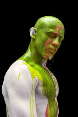 Gözleri kapalı duran genç adamın yaratıcı portresi. Renkli boyalar, boyalar kafasından, omuzlarından ve vücudundan aşağı akıyor..