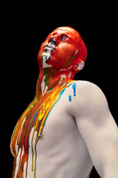 Kreatywny portret młodego człowieka stojącego z zamkniętymi oczami. Farby wielobarwne, barwniki spływają po jego głowie, ramionach i ciele. — Zdjęcie stockowe