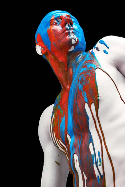 Gözleri kapalı duran genç adamın yaratıcı portresi. Renkli boyalar, boyalar kafasından, omuzlarından ve vücudundan aşağı akıyor..