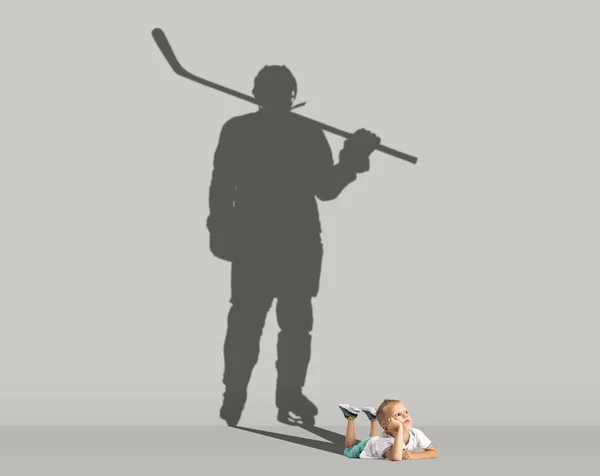 Fogalmi kép kisfiúval és árnyéka sportos férfi hoki játékos, bajnok szürke háttér. Gyermekkor, álmok, képzelet, oktatási koncepció. — Stock Fotó