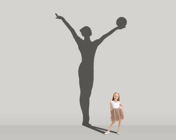 Les enfants et l'avenir. Image conceptuelle avec une petite fille rêvant de devenir gymnaste isolé sur un mur gris studio. Focus sur l'ombre — Photo