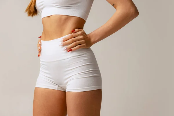 Обрізаний студійний знімок тонкого спортивного жіночого тіла в білій зручній білизні ізольовані на сірому фоні — стокове фото