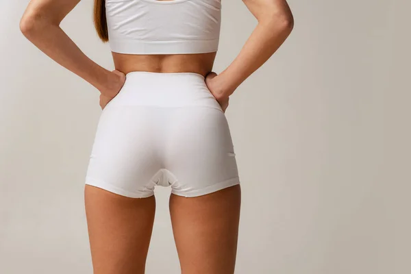 Αθλητικά μπουκάλια, πόδια. Περικοπή εικόνας του γυναικείου σώματος σε λευκό uderwear απομονώνονται σε γκρι φόντο στούντιο — Φωτογραφία Αρχείου