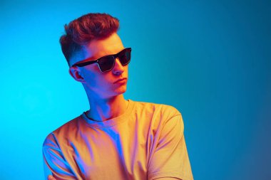 Gözlüklü öğrencinin mavi stüdyo arka planında izole edilmiş pozu. Aksiyon, spor, moda