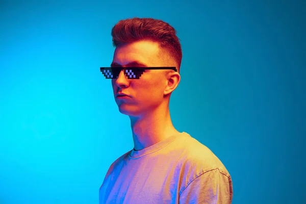 Captura de estudio de joven hombre emocional, estudiante en gafas posando aislado sobre fondo de estudio azul. Acción, deporte, moda — Foto de Stock