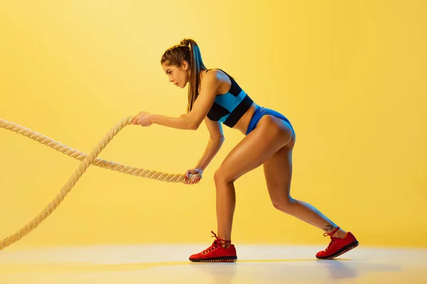 스포츠 밧줄을 가지고 훈련하는 젊은 스포츠 소녀의 모습 이 노란 스튜디오 배경에 고립되어 있다. 운동, 운동, 체력, 젊음 및 건강 개념. — 스톡 사진