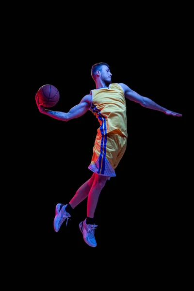 Porträt eines sportlichen Mannes, professioneller Basketballspieler, der isoliert auf dunklem Hintergrund in Neonlicht Basketball spielt. Erfolge, Sportkarriere, Bewegungskonzepte. — Stockfoto