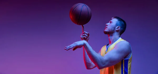 Gira. Estudio de tiro de hombre musculoso, entrenamiento de jugador de baloncesto con pelota aislada sobre fondo púrpura en luz de neón. Objetivos, deporte, movimiento, conceptos de actividad. — Foto de Stock
