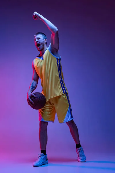Estudio de tiro de hombre musculoso, entrenamiento de jugador de baloncesto con pelota aislada sobre fondo púrpura en luz de neón. Objetivos, deporte, movimiento, conceptos de actividad. — Foto de Stock