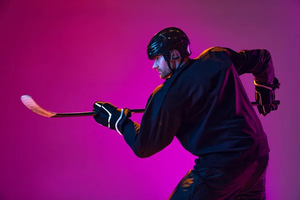 Treinamento de jogador de hóquei masculino profissional em uniforme especial com capacete isolado sobre fundo rosa em néon — Fotografia de Stock