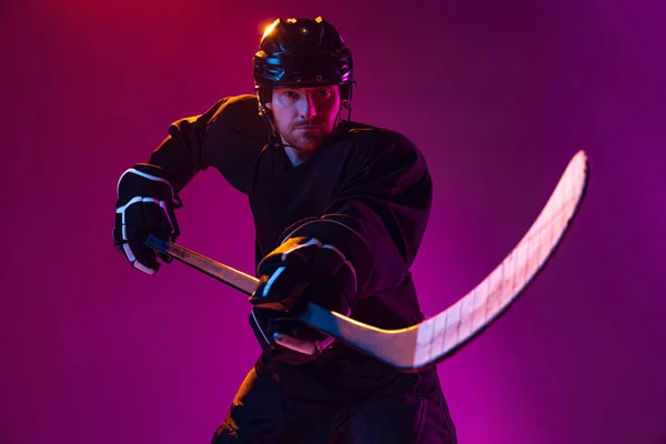 Jugador profesional de hockey masculino entrenando en uniforme especial con casco aislado sobre fondo rosa en neón. Campeón. —  Fotos de Stock